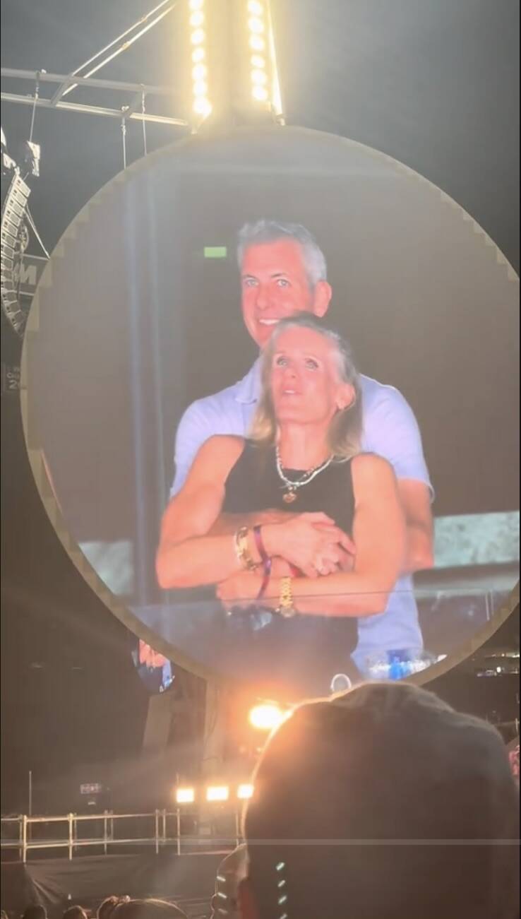 Andy Byron holds Kristin Cabot close as the two are shown on a large screen at a concert, looking emotional during the moment.